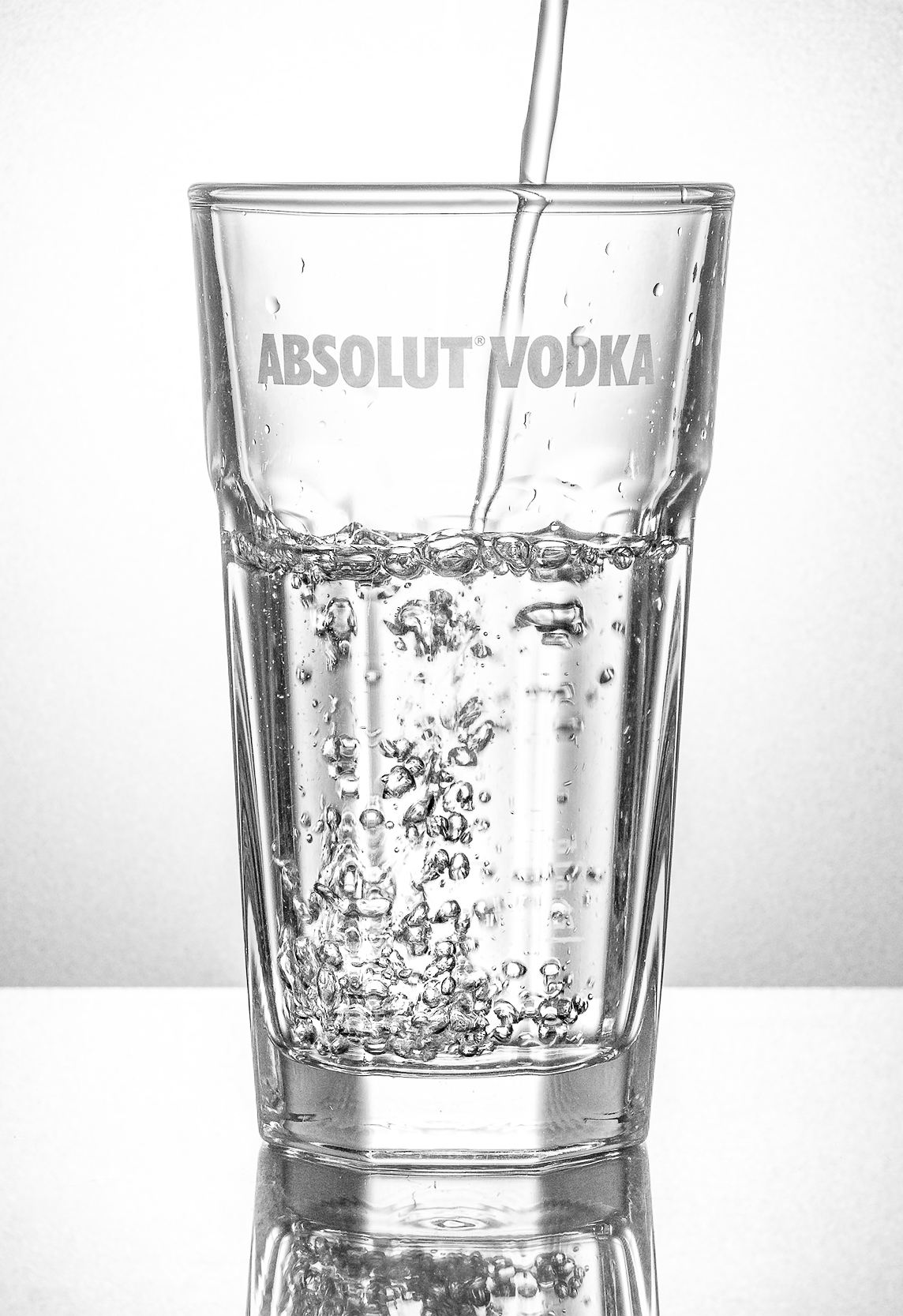 Produktfoto: Eine transparente Flüssigkeit fließt in ein Wodka-Glas