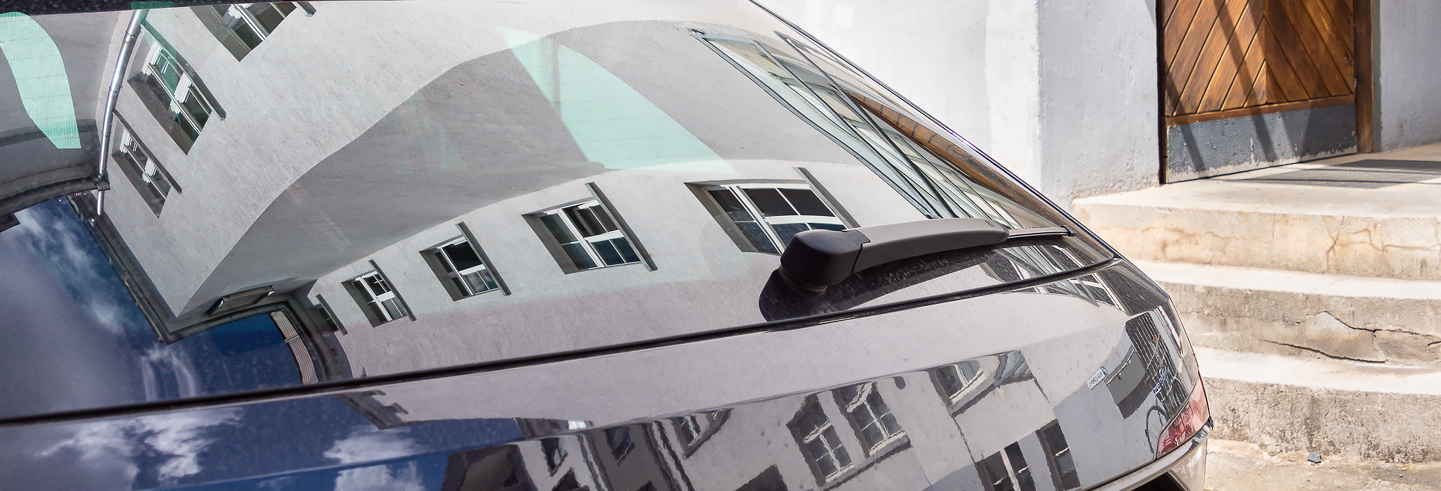 In den Scheiben des dpp-Firmenwagens spiegelt sich das Büro-Gebäude wider